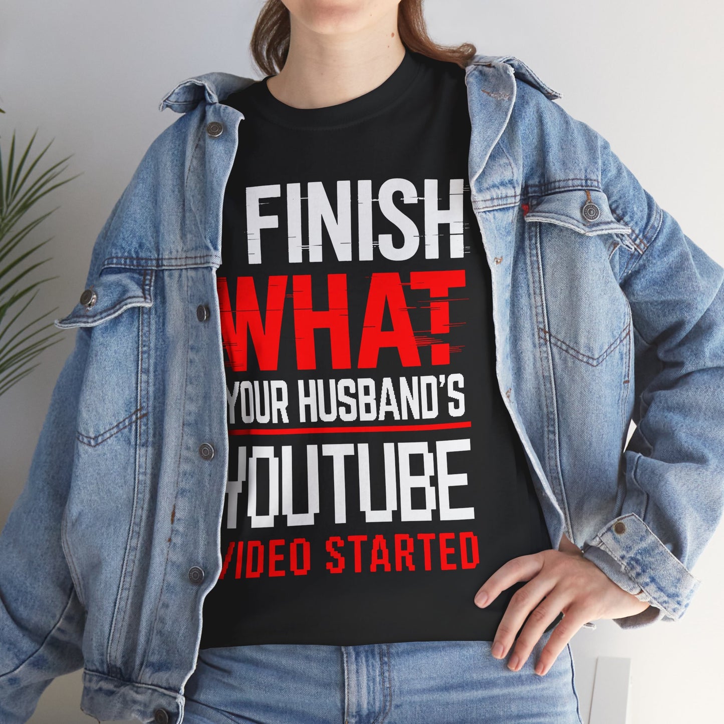 Person wearing a black t-shirt with humorous text design, standing indoors.