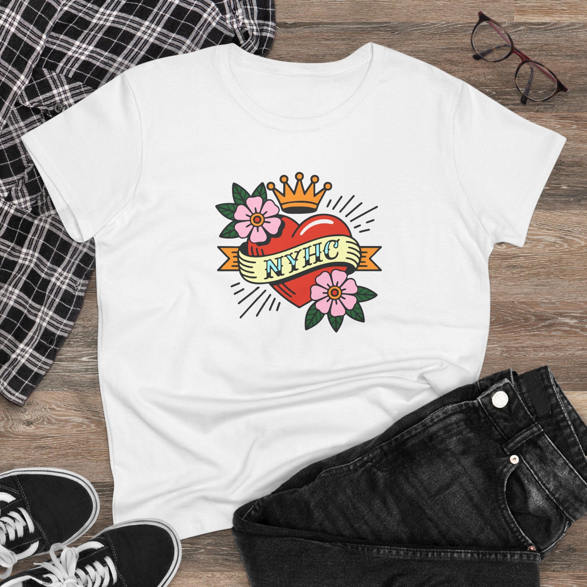 White t-shirt with a colorful NYHC graphic design on a wooden surface with casual clothing items.